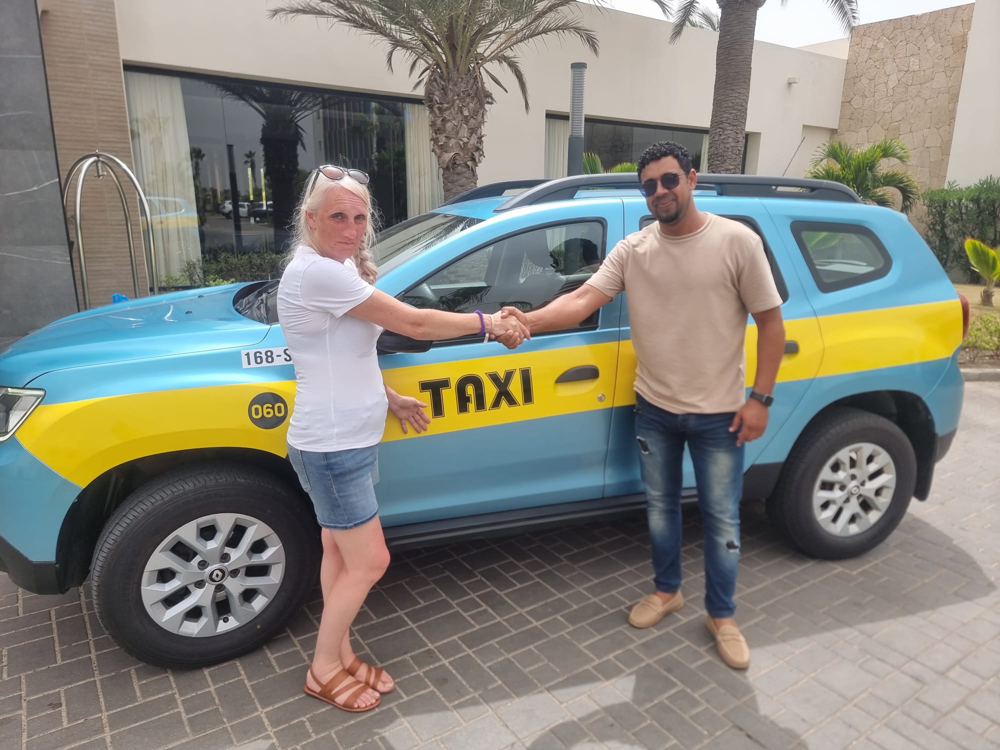 Djai greeting guests beside his taxi